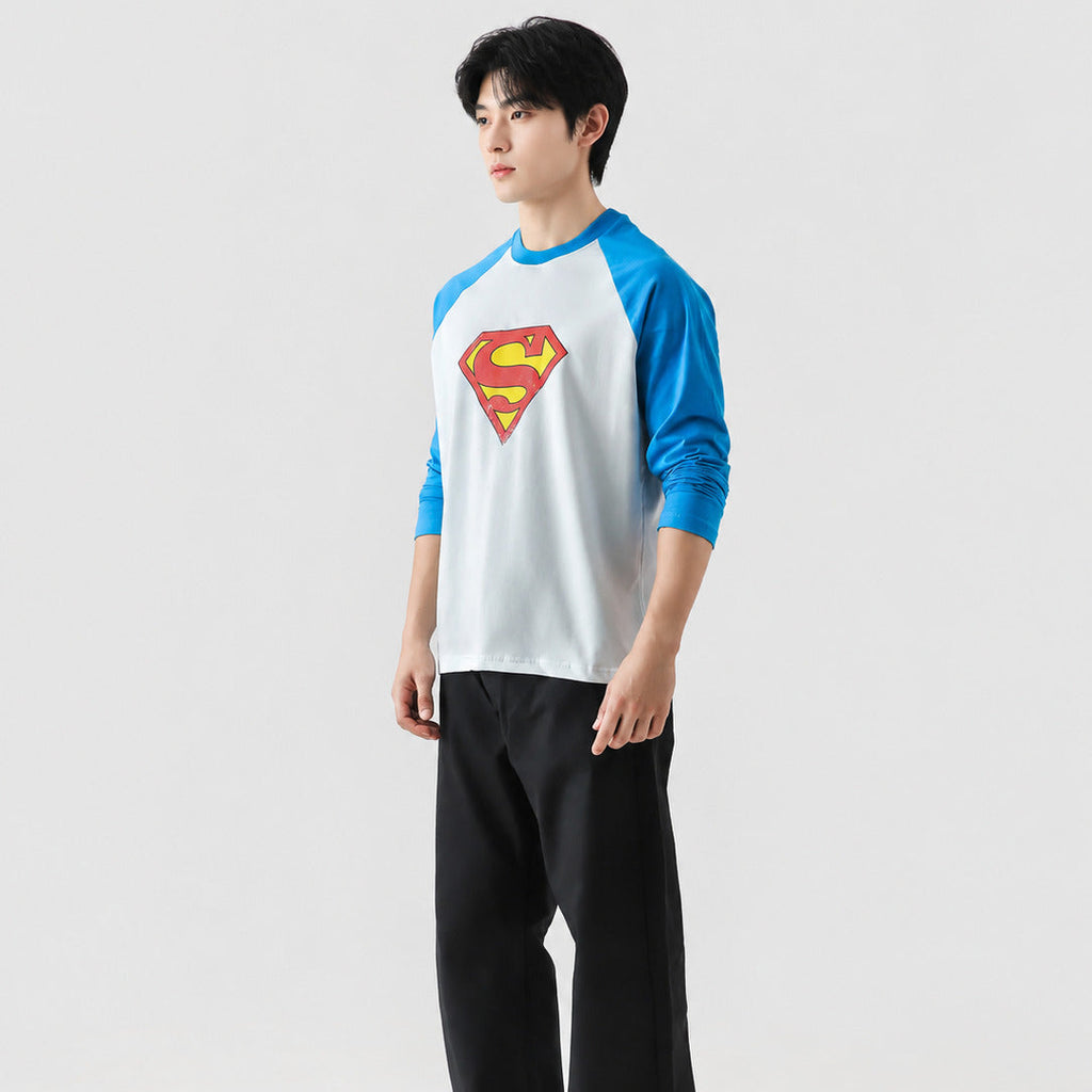 Person wearing a Superman logo shirt with blue sleeves on a white background