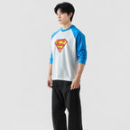 Person wearing a Superman logo shirt with blue sleeves on a white background