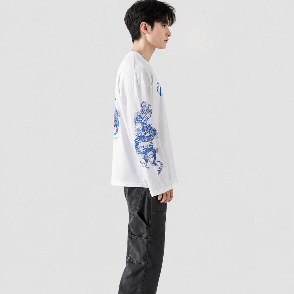 Person wearing a white shirt with blue dragon design and dark pants on a white background