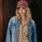 Woman wearing a maroon cap and blue denim jacket against a wooden background