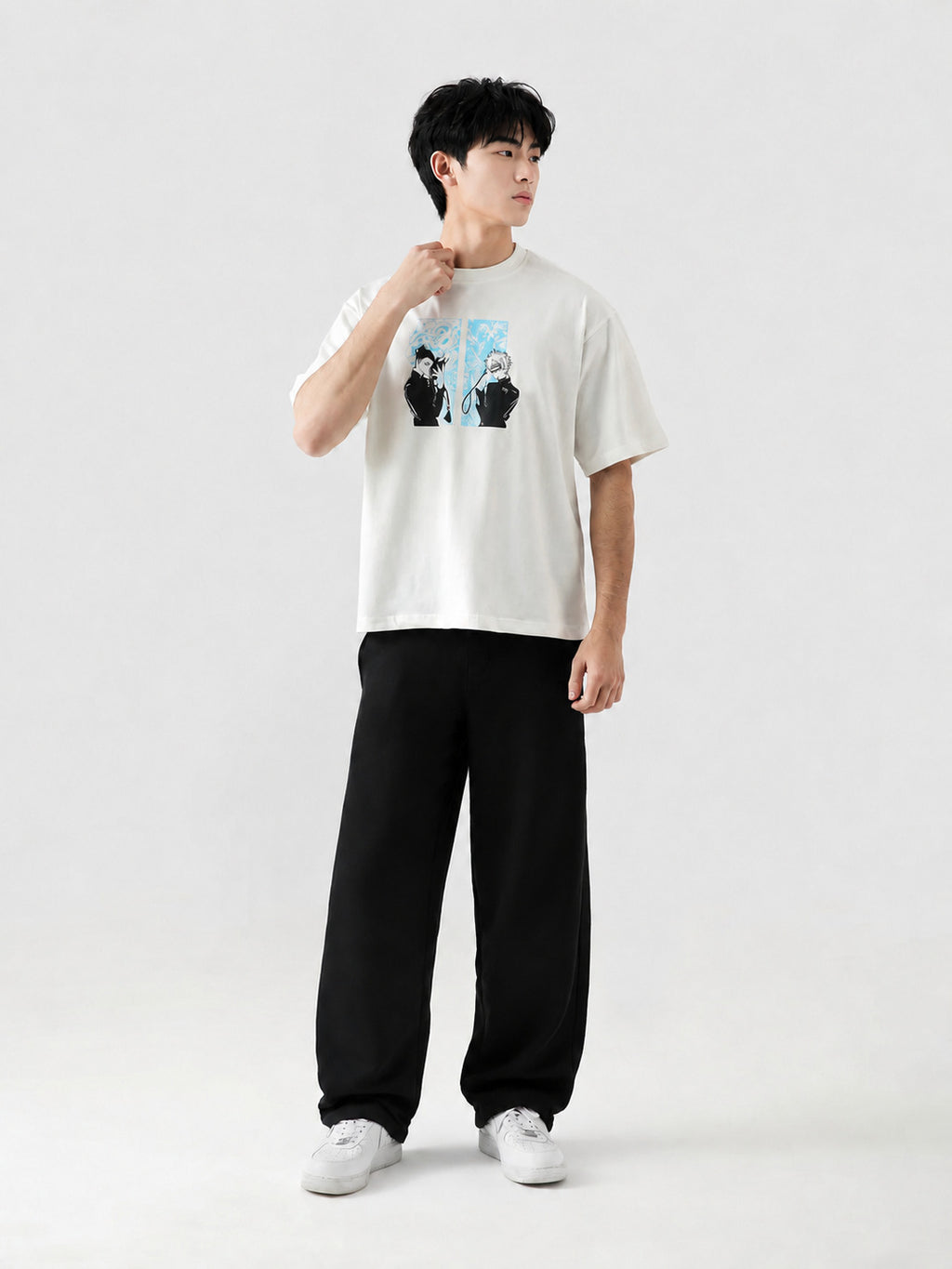 Person wearing a white t-shirt with a graphic design and black pants on a light gray background