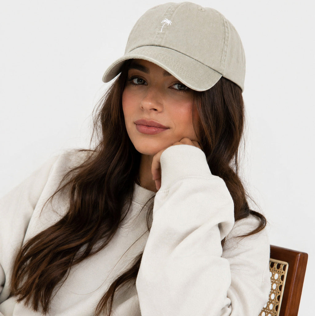 Woman wearing a beige cap and white sweater on a white background