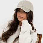 Woman wearing a beige cap and white sweater on a white background