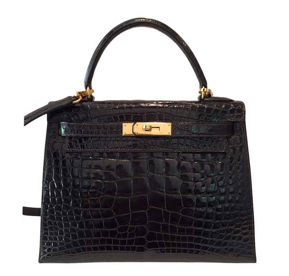 Black crocodile skin handbag with gold hardware on a white background