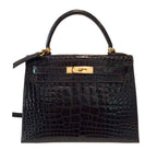 Black crocodile skin handbag with gold hardware on a white background
