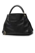 The bag carried on the forearm, highlighting its single braided strap